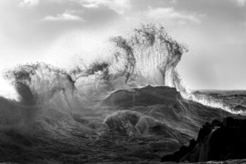 Black and white ocean wave crashing over rocks at Byron Bay, Australia, captured in dramatic coastal landscape photography.
