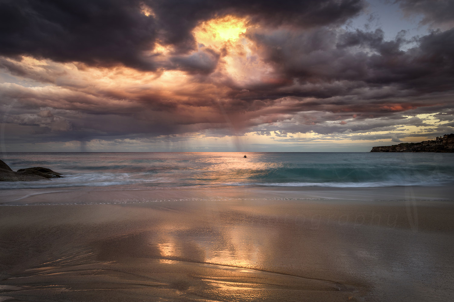 Dramatic sunset over Tamarama Beach with storm clouds, turquoise waves and golden reflections, Sydney, Australia.