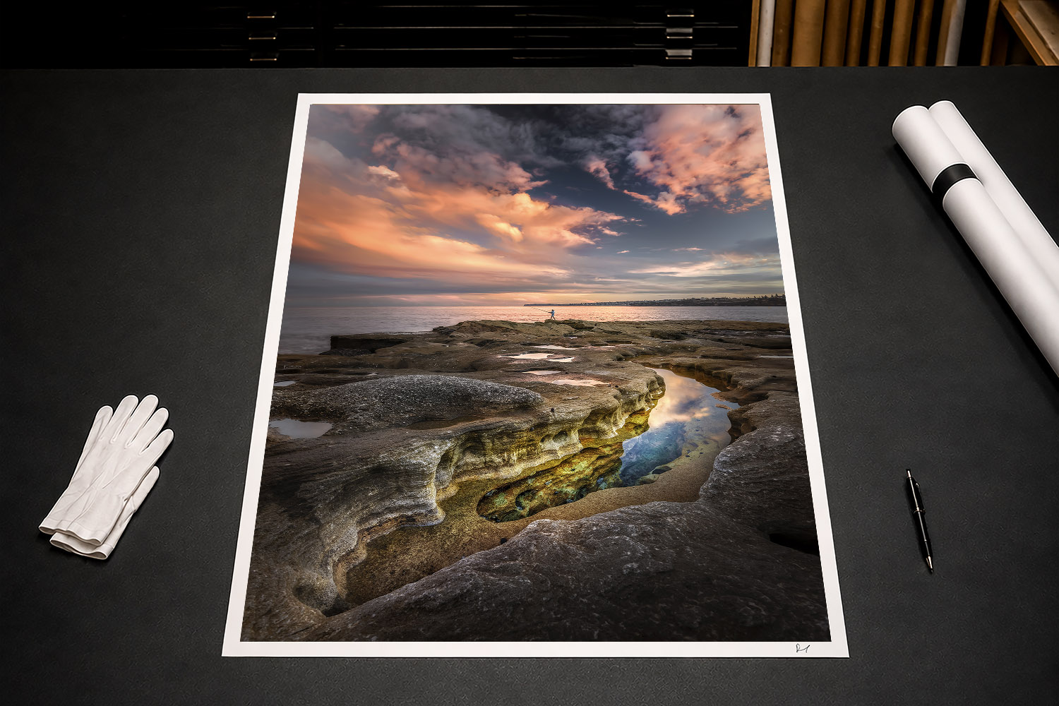 Fine art print of Bondi rock pools and a lone fisherman beneath dramatic sunset clouds in Sydney, Australia.