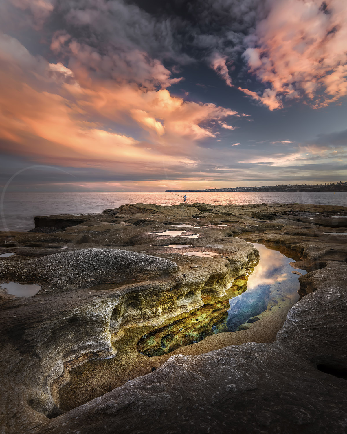 Rock pools and a lone fisherman at sunset in Bondi, Sydney, Australia, captured as fine art coastal landscape photography.