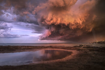 Dramatic storm clouds glowing at sunset over Tamarama Beach, Sydney, fine art coastal landscape photography.