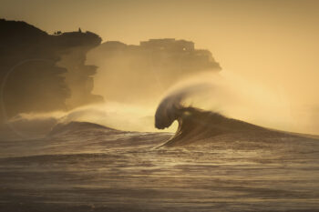 Golden wave breaking at sunrise at Bronte Beach, Sydney, with coastal cliffs behind, fine art ocean photography.