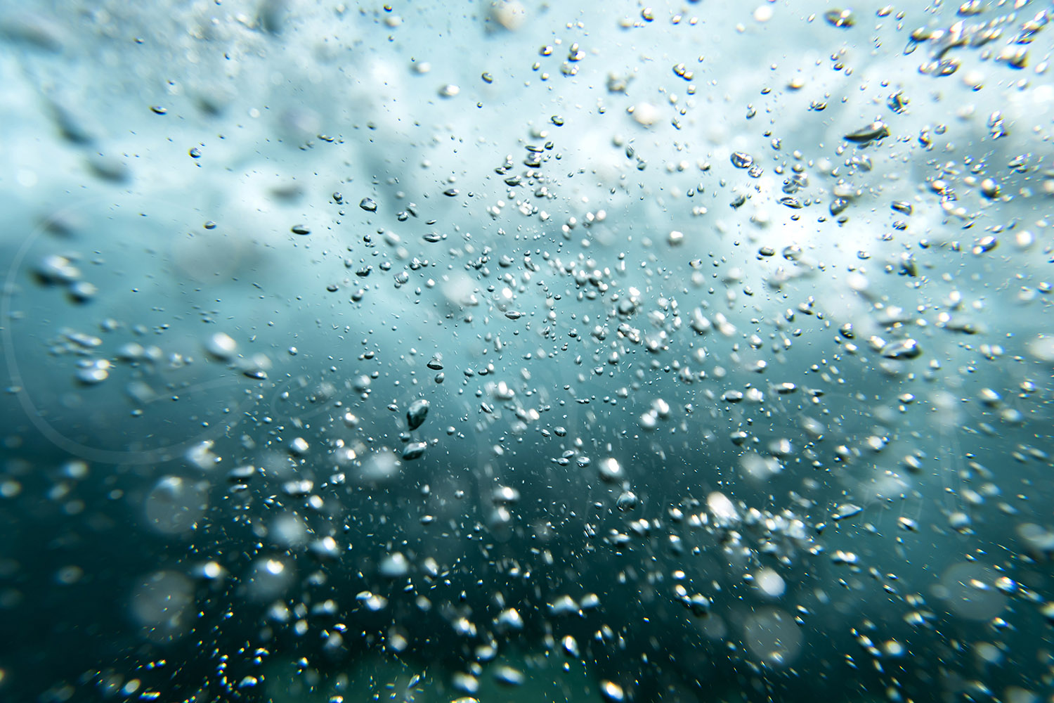 Underwater ocean bubbles rising through turquoise water beneath a breaking wave at Tamarama Beach, Sydney, Australia