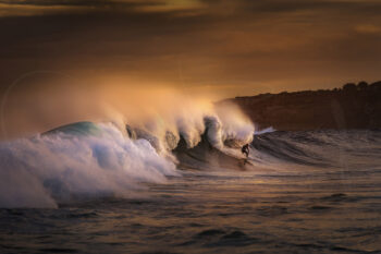 Surfer riding a breaking wave illuminated by golden sunset light at Tamarama Beach, Sydney, fine art surf photography.