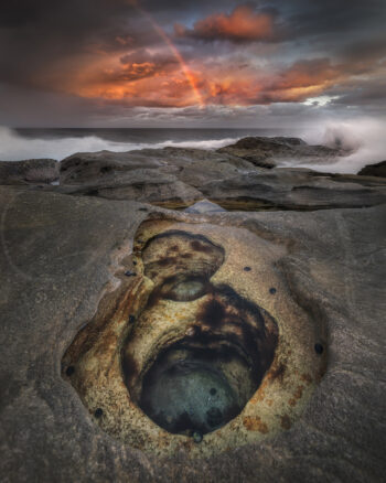 Rock pools, crashing waves and a rainbow at sunset in Bondi, Sydney, Australia, captured as fine art coastal photography.