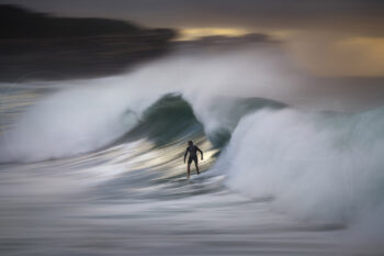 Surfer riding a wave at Bronte Beach sunrise, captured with motion blur creating a soft, painterly fine art photograph.