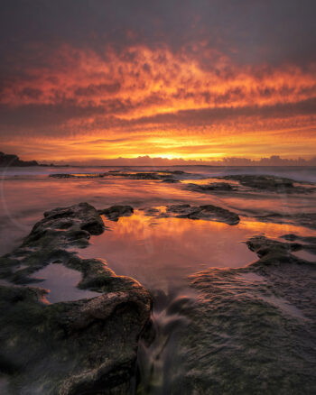 Fiery sunrise reflected across ocean rock pools at Maroubra Beach, Sydney, Australia, coastal seascape photography.