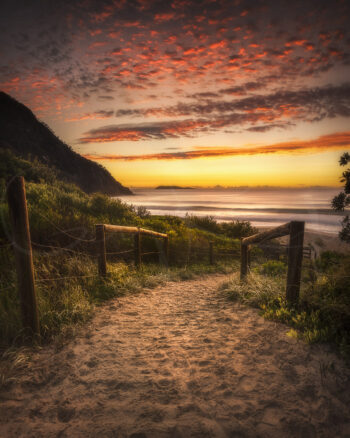 Sunrise over Zenith Beach in Port Stephens, NSW, with a sandy coastal path leading towards the ocean beneath glowing clouds.