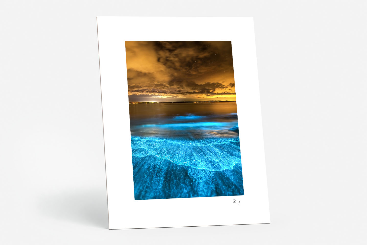 Mounted fine art print of electric blue bioluminescent waves beneath a dramatic golden night sky at Jervis Bay.
