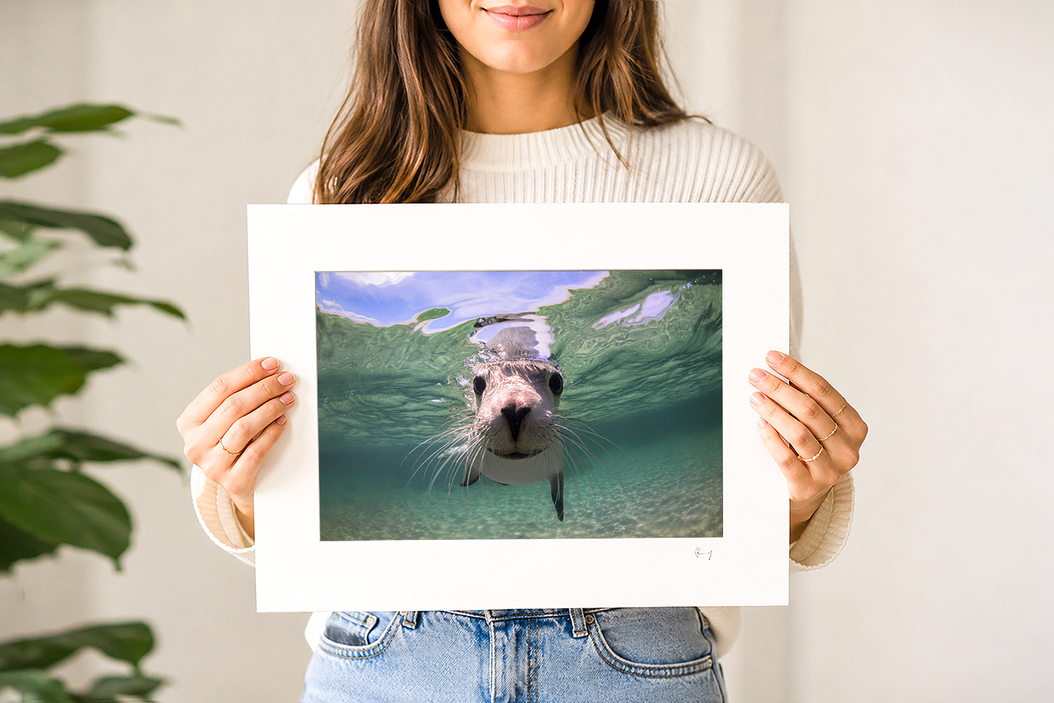 Woman holding a mounted fine art print of an Australian sea lion underwater at Baird Bay, South Australia.