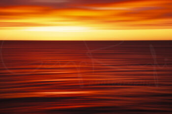 Abstract sunrise over the ocean at Bondi Beach, Sydney, with vivid red and orange motion blur, fine art coastal photography.