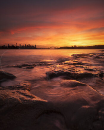 Fiery red and orange sunset over Sydney Harbour from Milk Beach, with city skyline and Harbour Bridge, fine art photography.