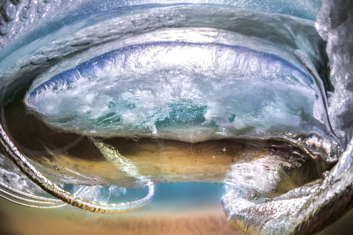 Underwater wave vortex at Byron Bay, Australia, with swirling water, bubbles and reflections beneath the ocean surface