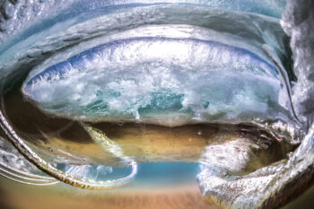 Underwater wave vortex at Byron Bay, Australia, with swirling water, bubbles and reflections beneath the ocean surface
