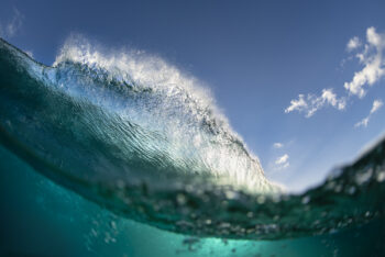 Fine art print of a dramatic wave on the Gold Coast, Queensland, with sunlight bursting through and a vivid blue sky above.