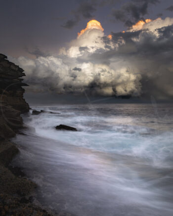 Stormy sunset over the ocean and rocky coastline at Tamarama Beach, Sydney, Australia, fine art seascape photography.
