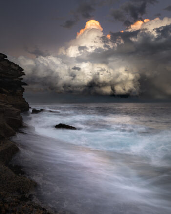 Award-winning fine art ocean print of towering storm clouds illuminated at sunset over Tamarama Beach, Sydney – "Sugarloaf Summit"
