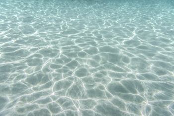 Mounted fine art print of shimmering shallow water at Jervis Bay, Australia, where sunlight dances across the sand in gentle patterns.