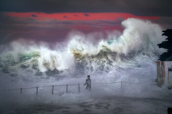 Award-winning photograph of a lone swimmer facing enormous waves at Bronte Beach, Sydney, beneath a dramatic sunset sky.
