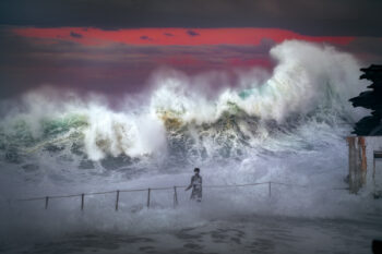 Award-winning seascape photograph of a lone figure standing before massive storm waves at Bronte Beach, Sydney, Australia.