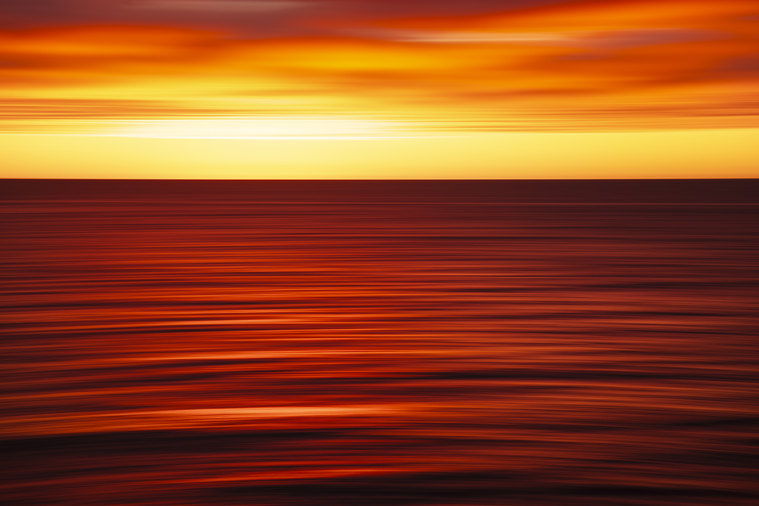 Abstract ocean sunrise at Bondi Beach, Sydney, with vivid red, orange and golden light reflected across the moving sea.