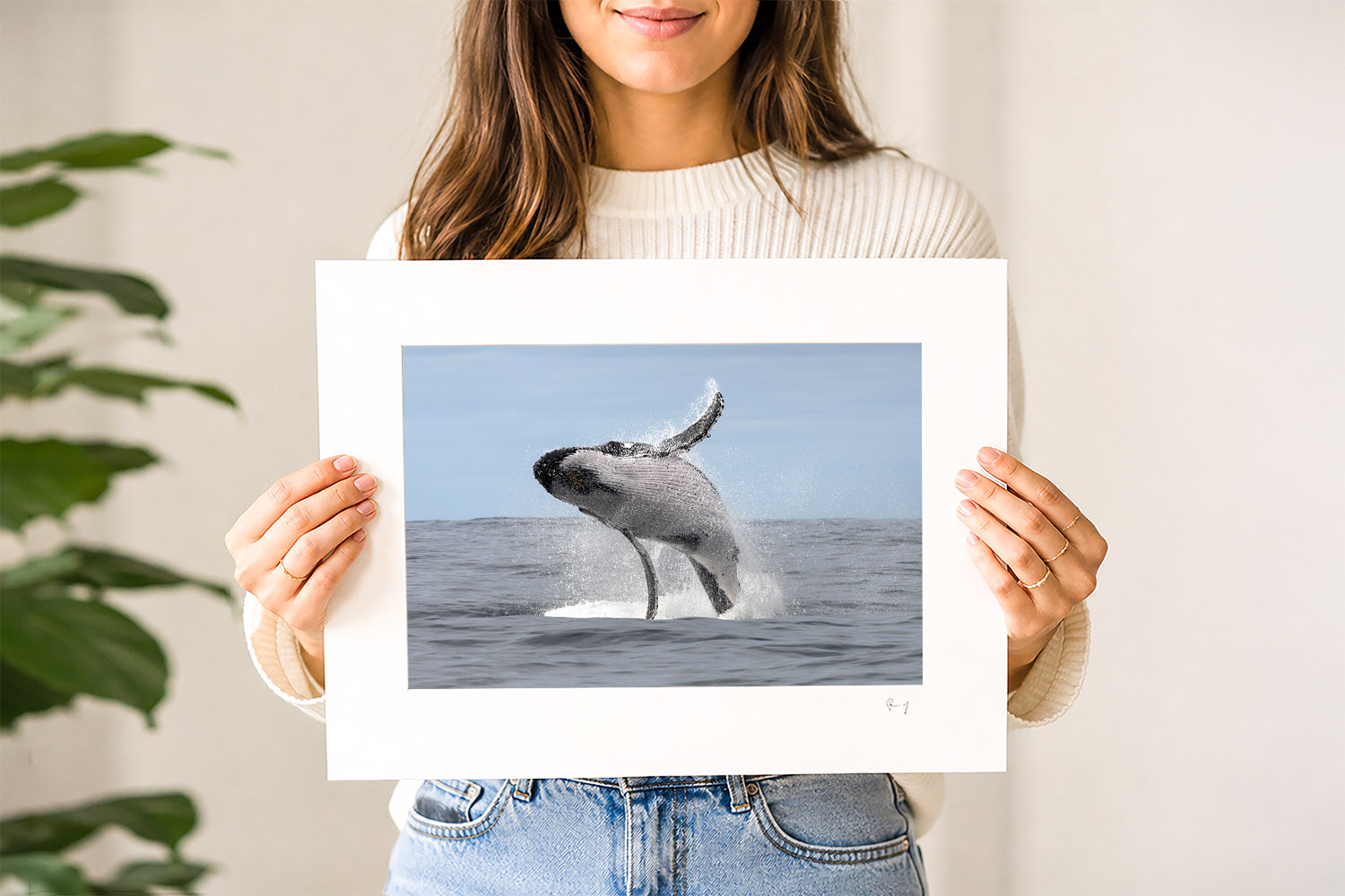 Woman holding a mounted fine art print of a breaching humpback whale photographed at Port Stephens, Australia.